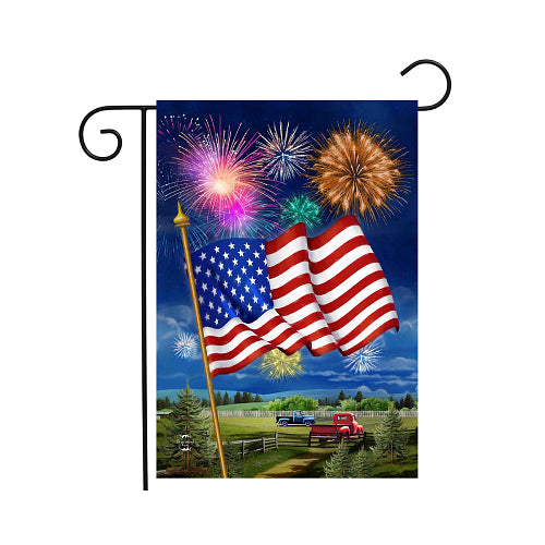 Garden flag with American flag and fireworks against a blue sky
