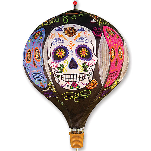 A decorative hot air balloon featuring a colorful sugar skull design on a black background, with a small woven basket at the bottom