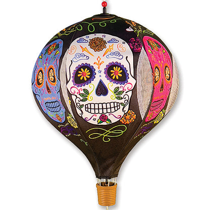 A decorative hot air balloon featuring a colorful sugar skull design on a black background, with a small woven basket at the bottom