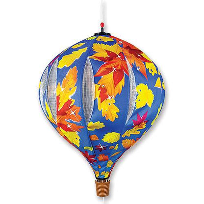 A hot air balloon-shaped hanging ornament or lantern with a blue background and a pattern of colorful autumn leaves in yellow, orange, red, and pink. It features vertical white mesh panels on the sides and a brown woven basket-like bottom.