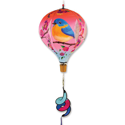 A decorative hot air balloon wind spinner featuring a pink and orange balloon with a bluebird design, a gold-colored basket, and a blue, pink, and orange spiral tail, shown against a plain white background.