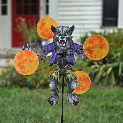 Werewolf Halloween whirligig spinner staked in a yard flower bed with spinning moons