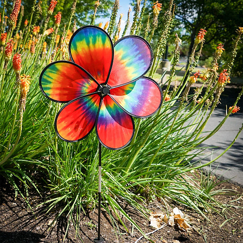 Outdoor view of the colorful tie-dye flower-shaped wind spinner in a garden setting.