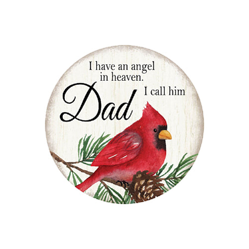 Round decorative sign featuring a red cardinal perched on pine branches with the text 'I have an angel in heaven. I call him Dad' on a light wood-textured background.