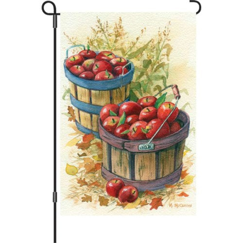 Decorative garden flag with apples in wooden baskets and autumn leaves.