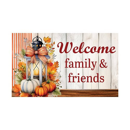 Decorative fall doormat with pumpkins, lantern, and autumn leaves on a wooden background with 'Welcome family & friends' text.