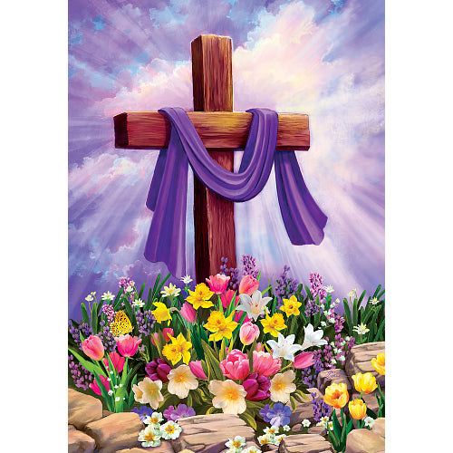 Wooden cross with purple cloth, surrounded by colorful flowers and rocks against a purple sky.