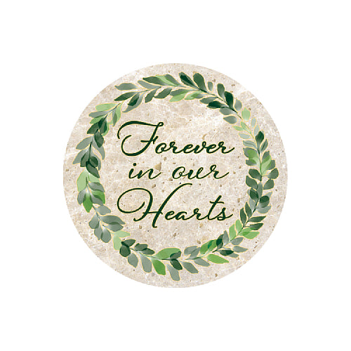 A round decorative plaque or coaster with a beige stone-like background, featuring a green leaf wreath and the phrase 'Forever in our Hearts' in dark green cursive script.