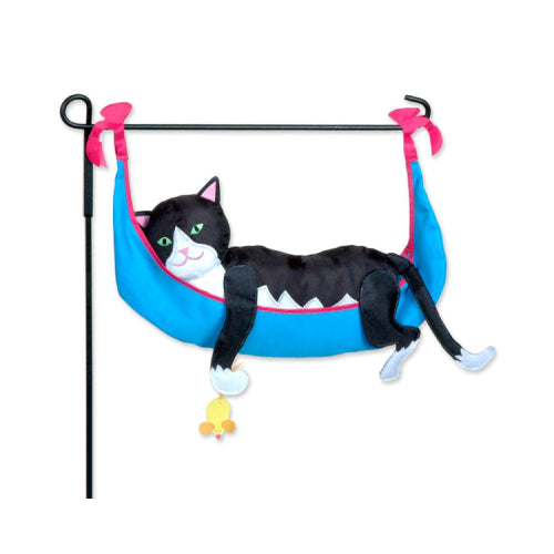 A black and white cat plush toy hanging in a blue hammock with pink trim, suspended from a black metal stand.