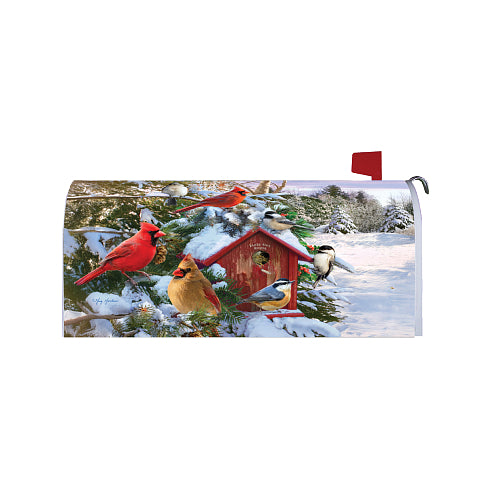 A rectangular mailbox cover featuring a winter bird scene with snow-covered evergreen branches, a red birdhouse, and several colorful birds including cardinals, titmice, and a bluebird. The cover is shown mounted on a white mailbox with a red flag, isolated on a white background.