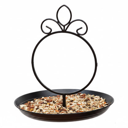 A wrought iron Suncatcher bird feeder with a decorative black metal frame. The Suncatcher frame sits on a black tray filled with birdseed.