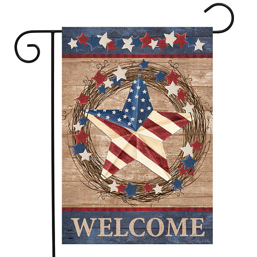 Decorative, primitive-style flag with an American flag and wreath design and 'WELCOME' text on a wooden background.